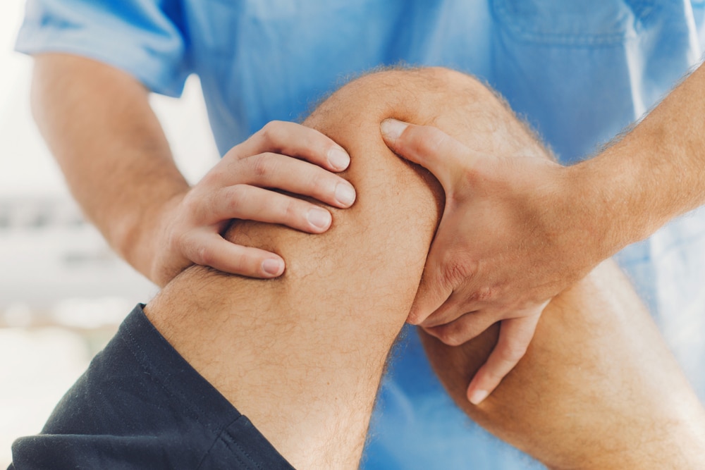 Osteopath treating patient for knee pain