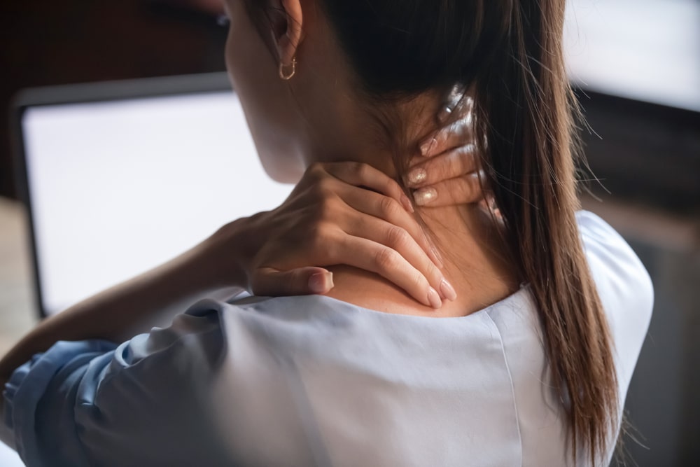 Young woman holding neck in pain
