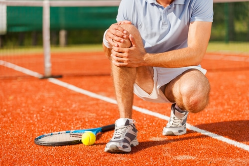 Tennis player holding knee in pain