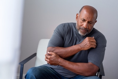 Older man holding elbow in pain