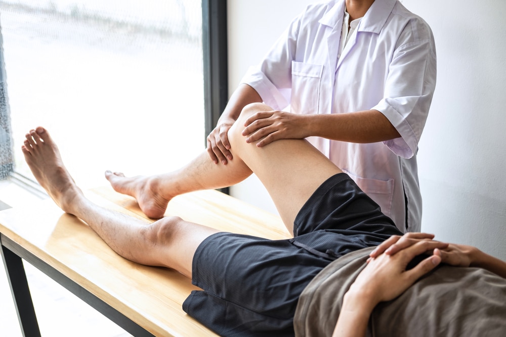 Osteopath treating patient with knee pain