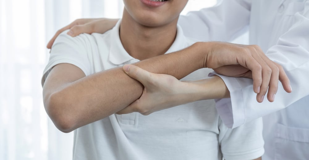 Osteopath treating young patient holding arm and shoulder