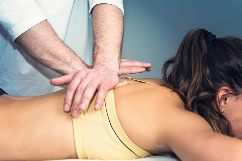 Young woman receiving osteopathic treatment to her back