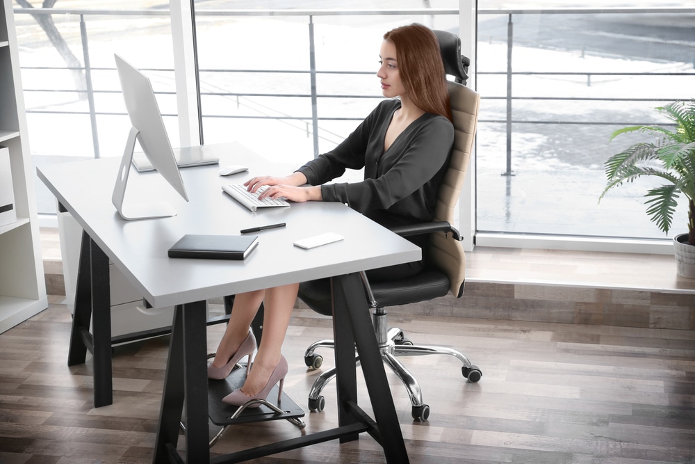 Young woman sitting at desk in ergonomic chair