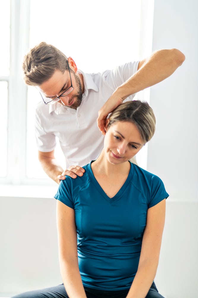 Male osteopath treating woman for neck pain